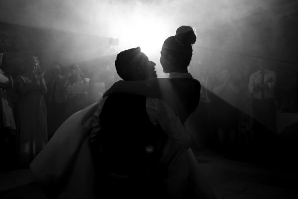 Fotografía de boda durante el baile nupcial. Contraluz nocturno aprovechando los reflejos del humo artificial.