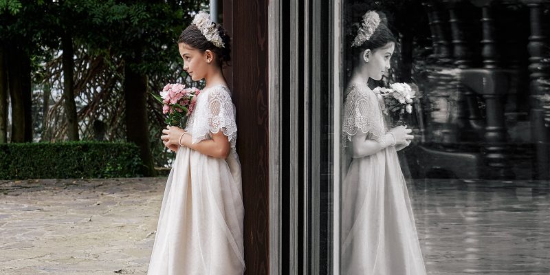 Retrato de comunión - Niña con ramo reflejada en ventanal.
